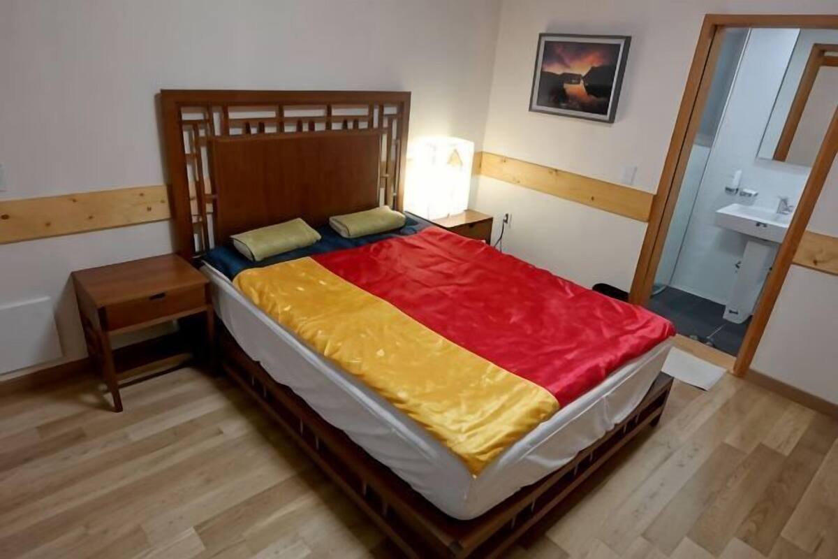 Uma cama com cabeceira de madeira, mesa de cabeceira e criado-mudo.