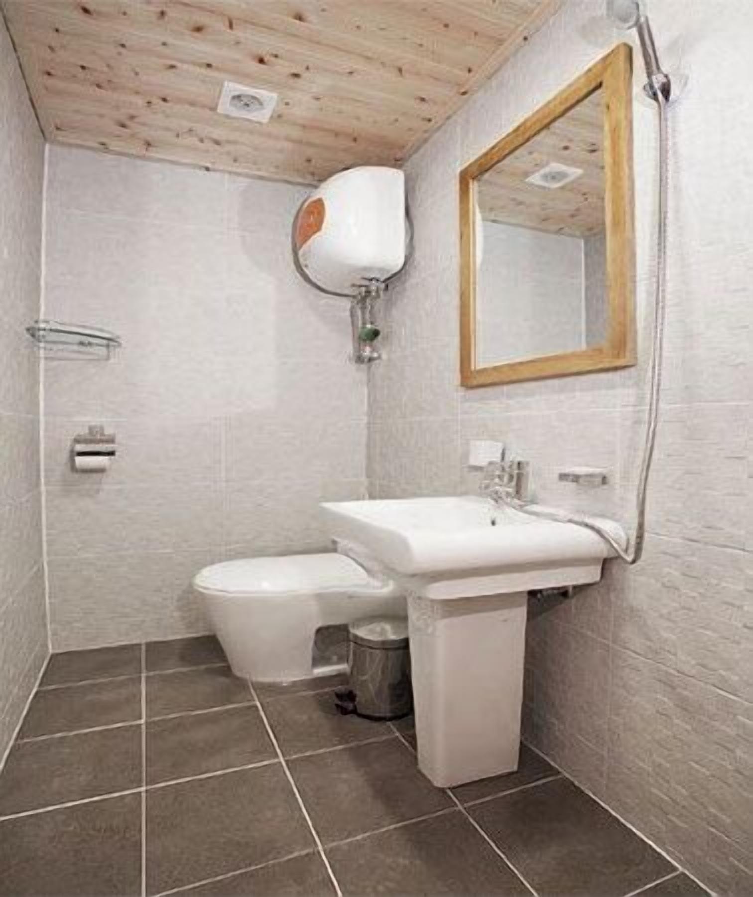 A small bathroom with a toilet, sink, and mirror.