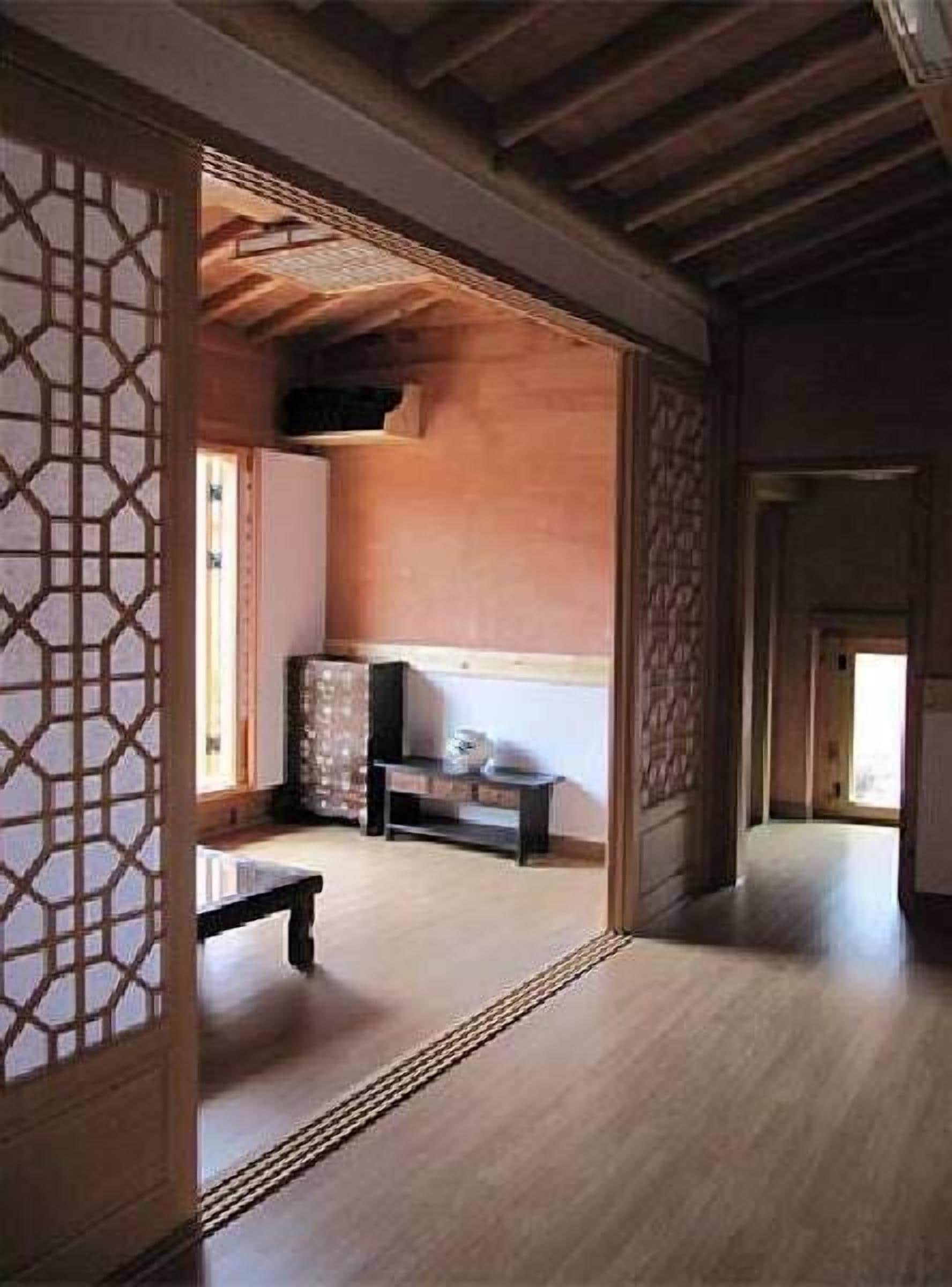 A traditional Japanese room with tatami flooring, a low wooden ceiling, and sliding doors with geometric patterns.