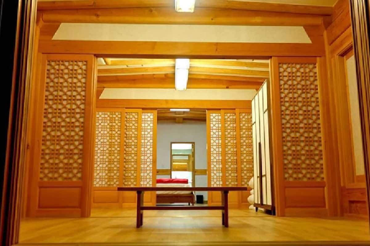 Um quarto japonês tradicional com tatames, uma mesa de madeira baixa e portas deslizantes com desenhos em treliça.