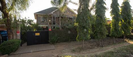 A residential property with a gated entrance, a paved driveway, and a variety of trees and shrubs.