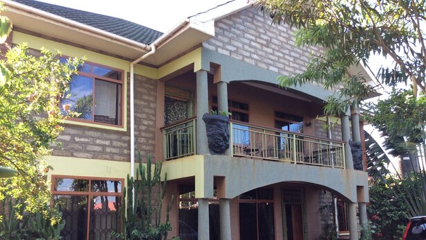 A two-story building with a balcony, outdoor seating, and a car parked in front. - Korona Villa Bed & Breakfast (Arusha)