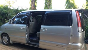 A silver van with a sliding door, parked on a paved surface. - Korona Villa Bed & Breakfast (Arusha)