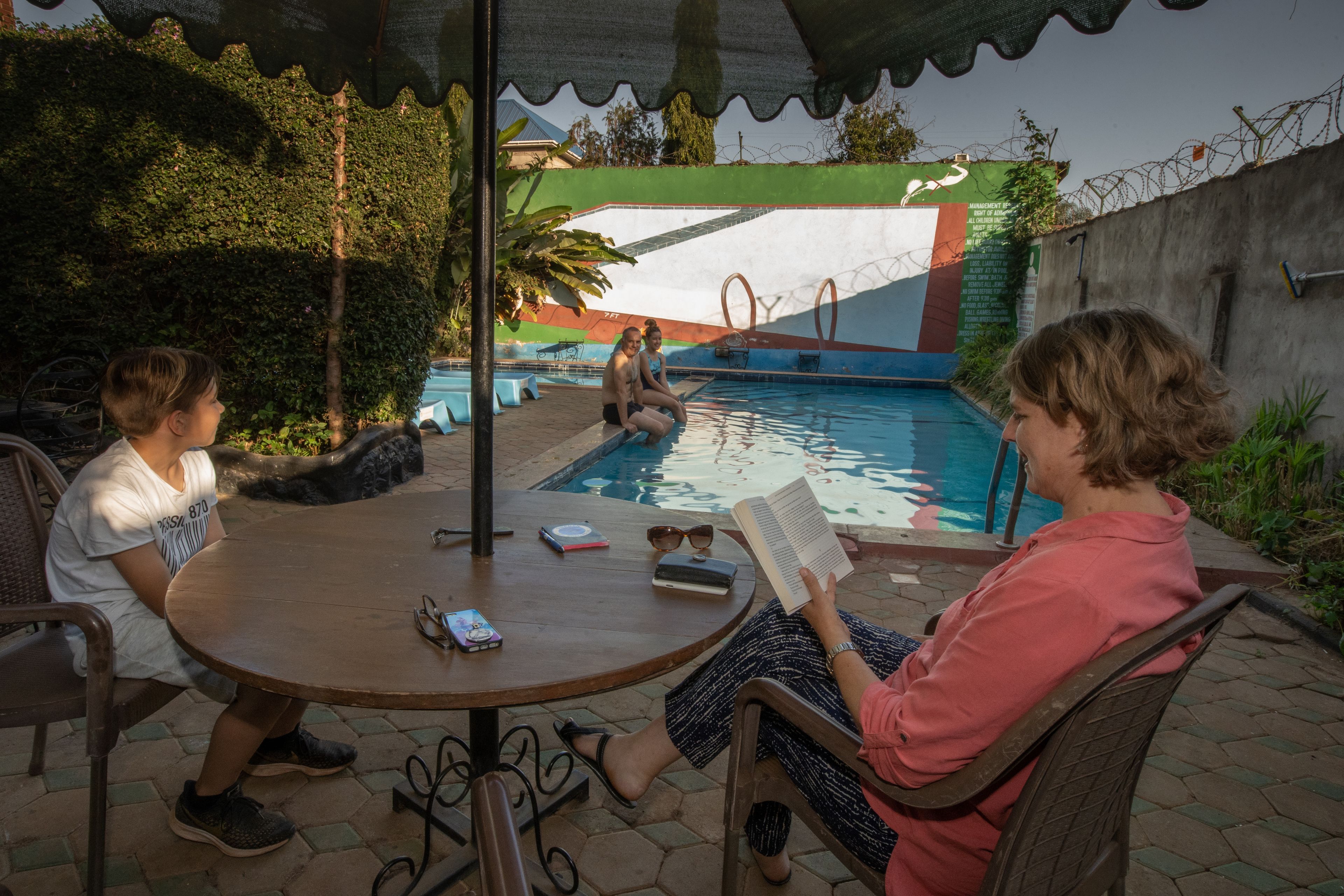 Zona piscina con tavolo rotondo, sedie e piscina.