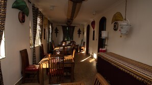 A dining area with wooden furniture, patterned curtains, and a view of the dining room. - Korona Villa Bed & Breakfast (Arusha)