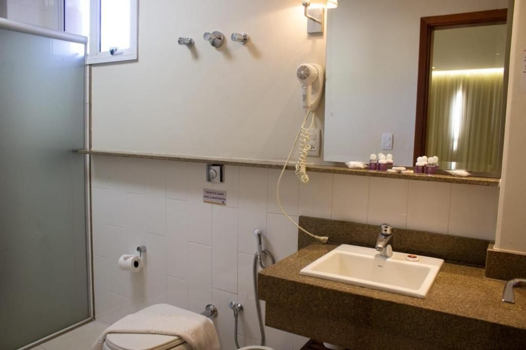 A bathroom with a sink, mirror, towel, and a hairdryer.