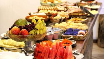 Un bufé con diversas frutas y postres.