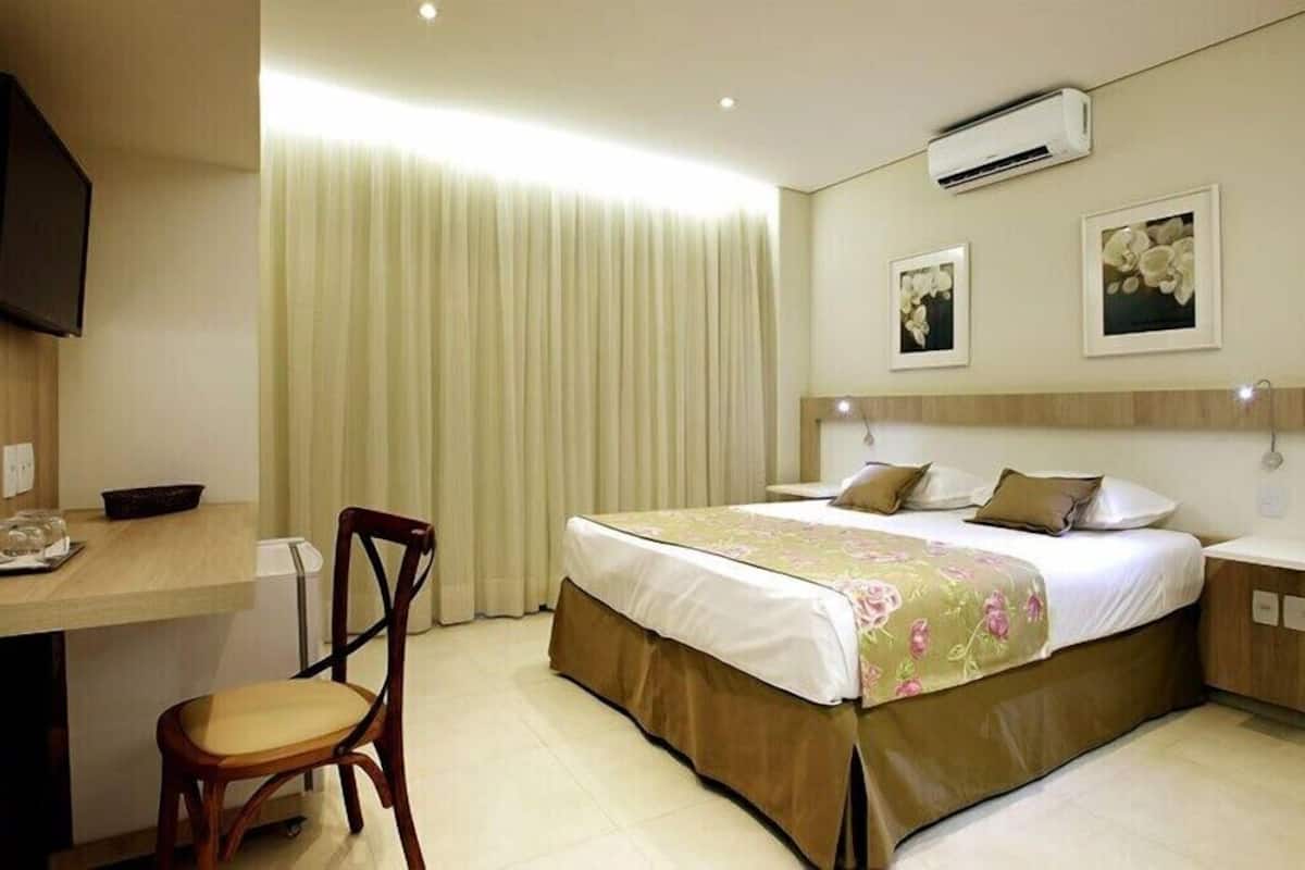 A hotel room with a bed, a desk, and a chair.