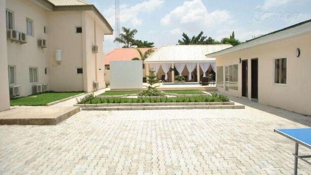Une cour comprenant une zone pavée, un petit jardin et un bâtiment doté d’un espace de repos abrité.