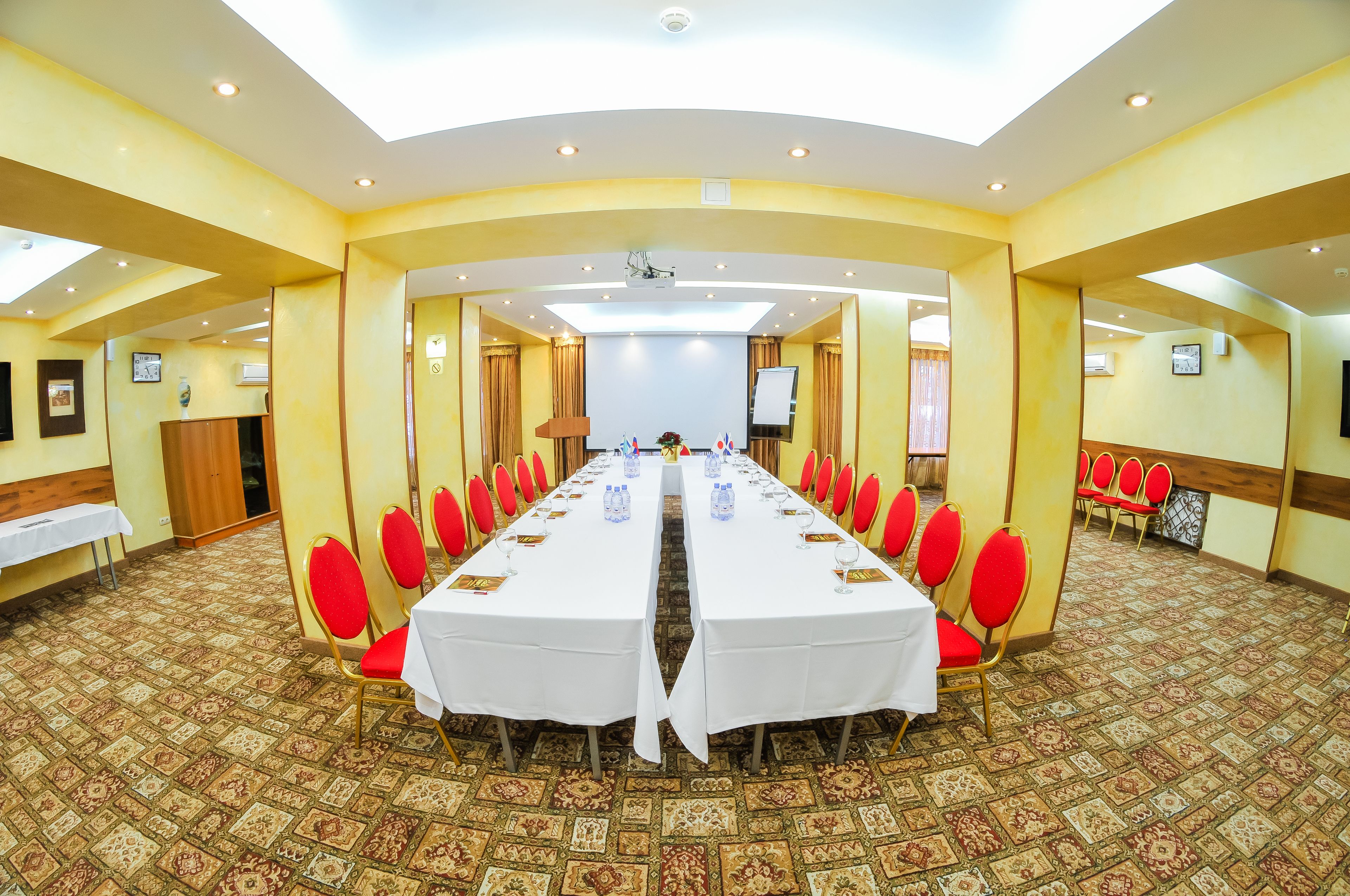 A conference room with a long table, red chairs, and carpeted floors.