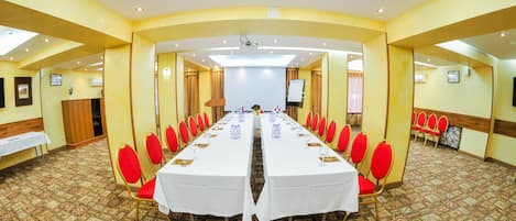 A conference room with a long table, red chairs, and carpeted floors.