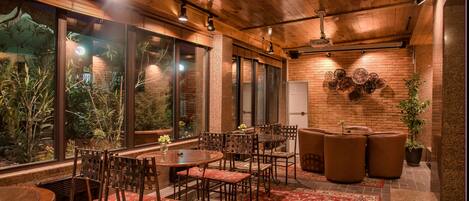A dining area with wooden furniture, large windows, and a brick wall with decorative plates.