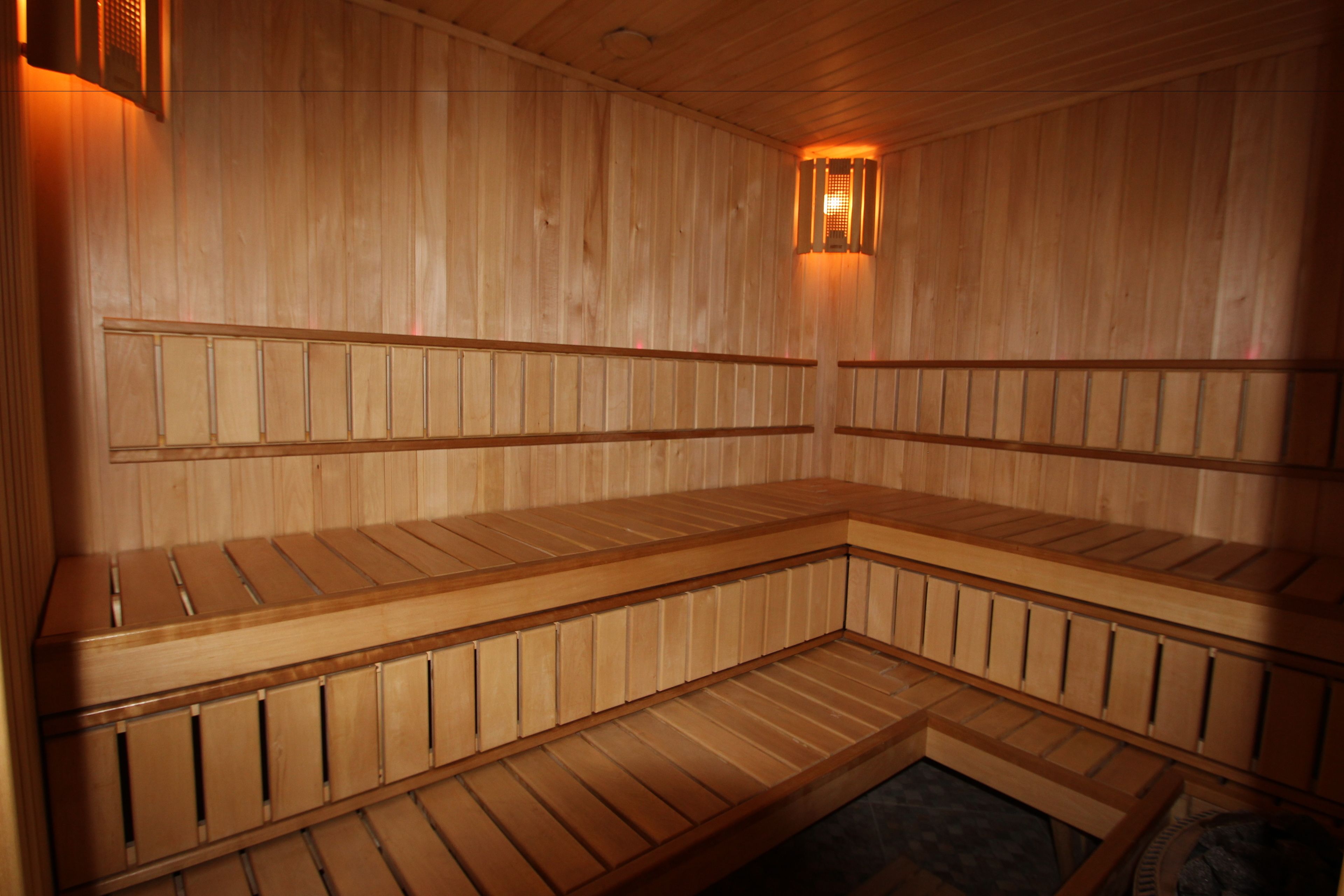 Una sauna con bancos de madera y una lámpara en la pared.