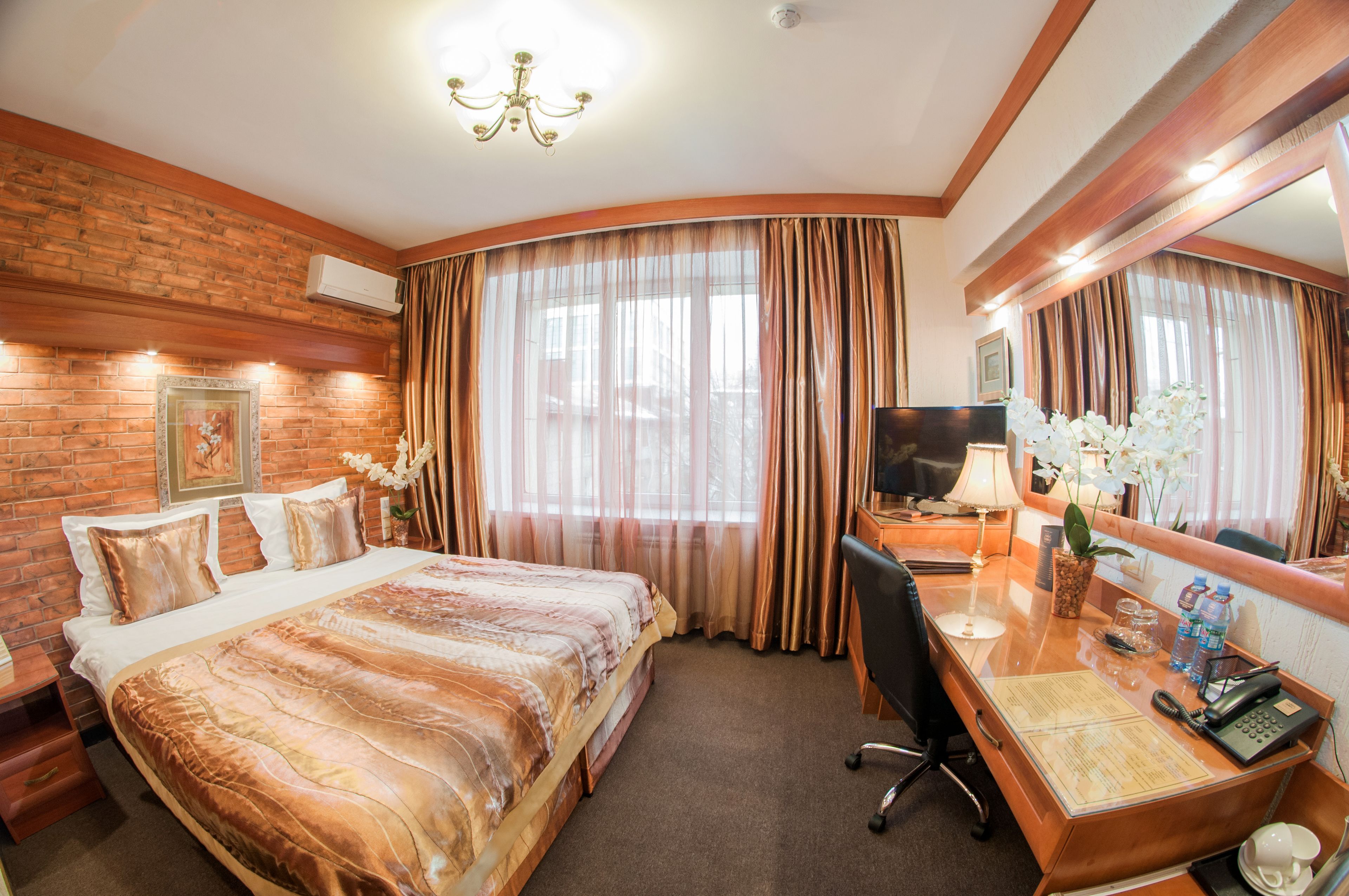 Une chambre d’hôtel avec un grand lit, un bureau avec un ordinateur, une télévision et une salle de bain avec douche et toilettes.