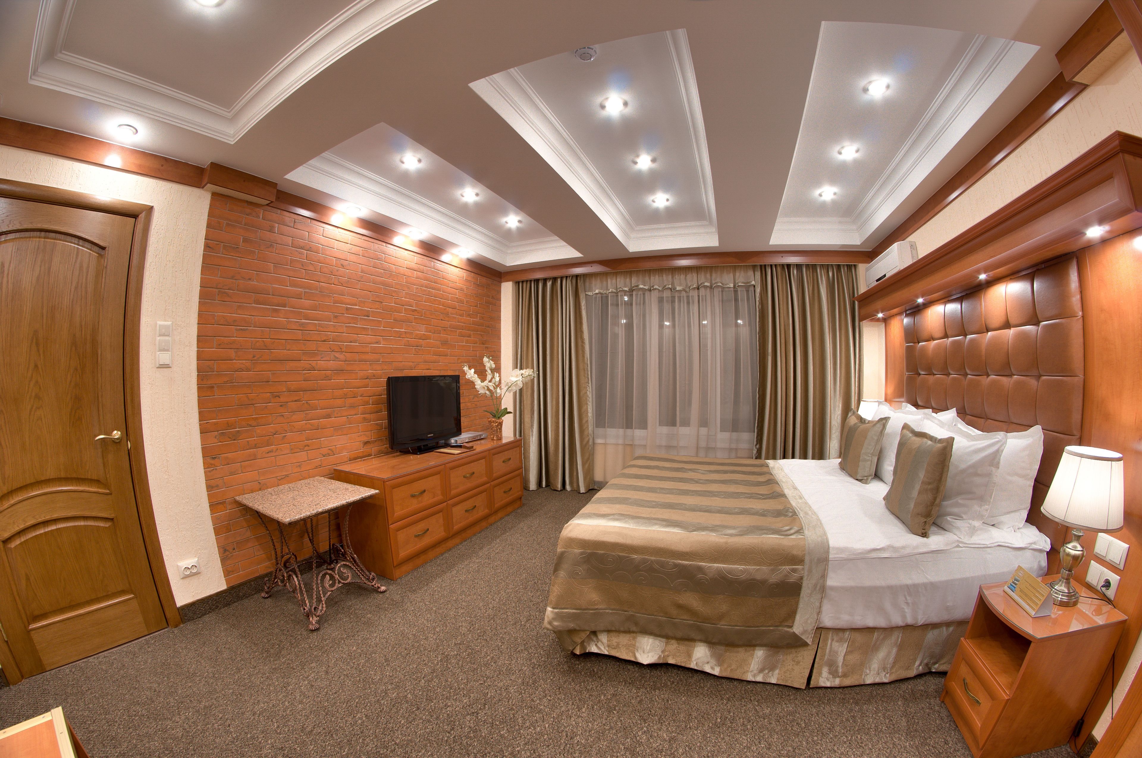 Une chambre d’hôtel avec un lit, une télévision, un bureau et une fenêtre avec des rideaux.