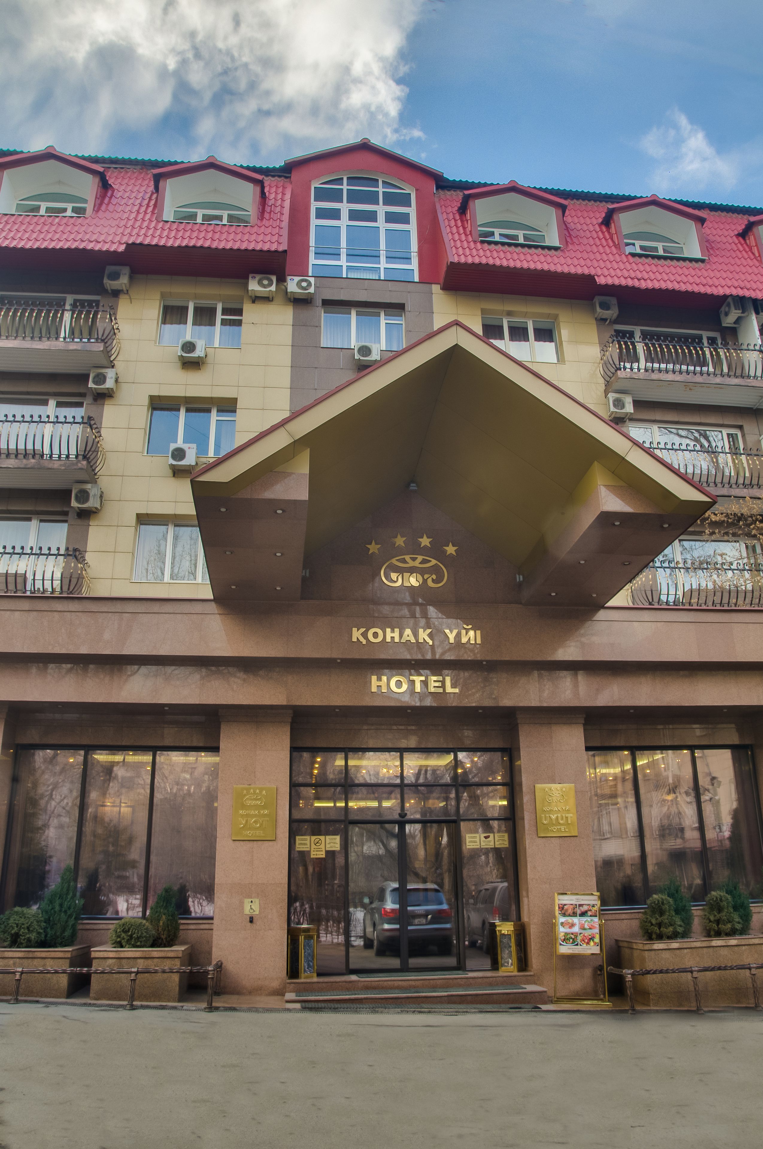 A hotel entrance with a red roof, a sign reading "KONAK YI HOTEL," and air conditioning units on the facade.
