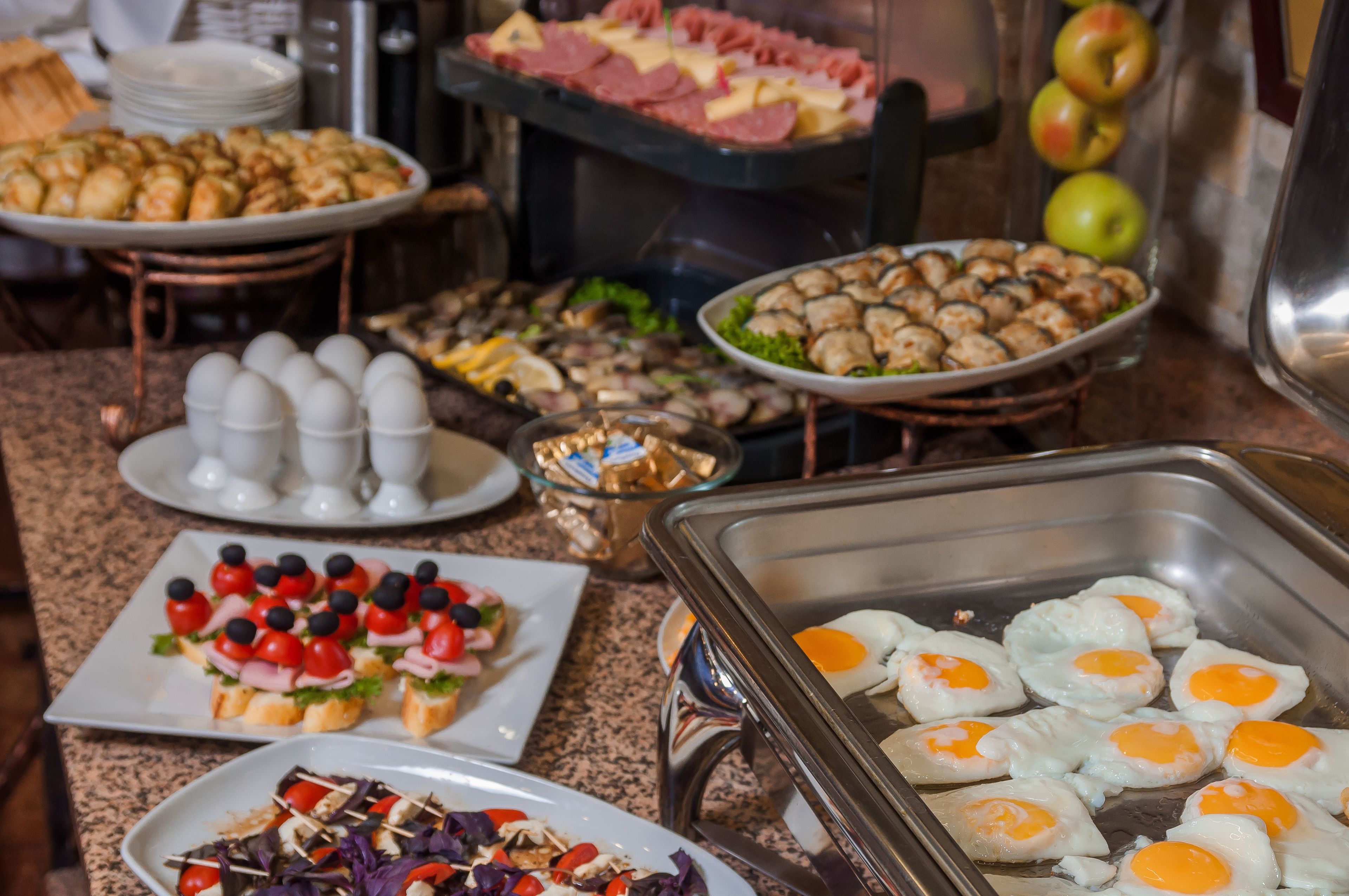 Un bufé con diferentes opciones de comida, como huevos, ensaladas y carnes.