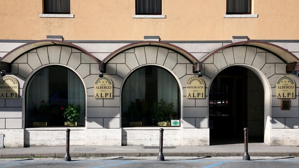 Fachada de edificio con tres ventanas arqueadas, cada una con un letrero que dice "Ristorante delle ALPI".