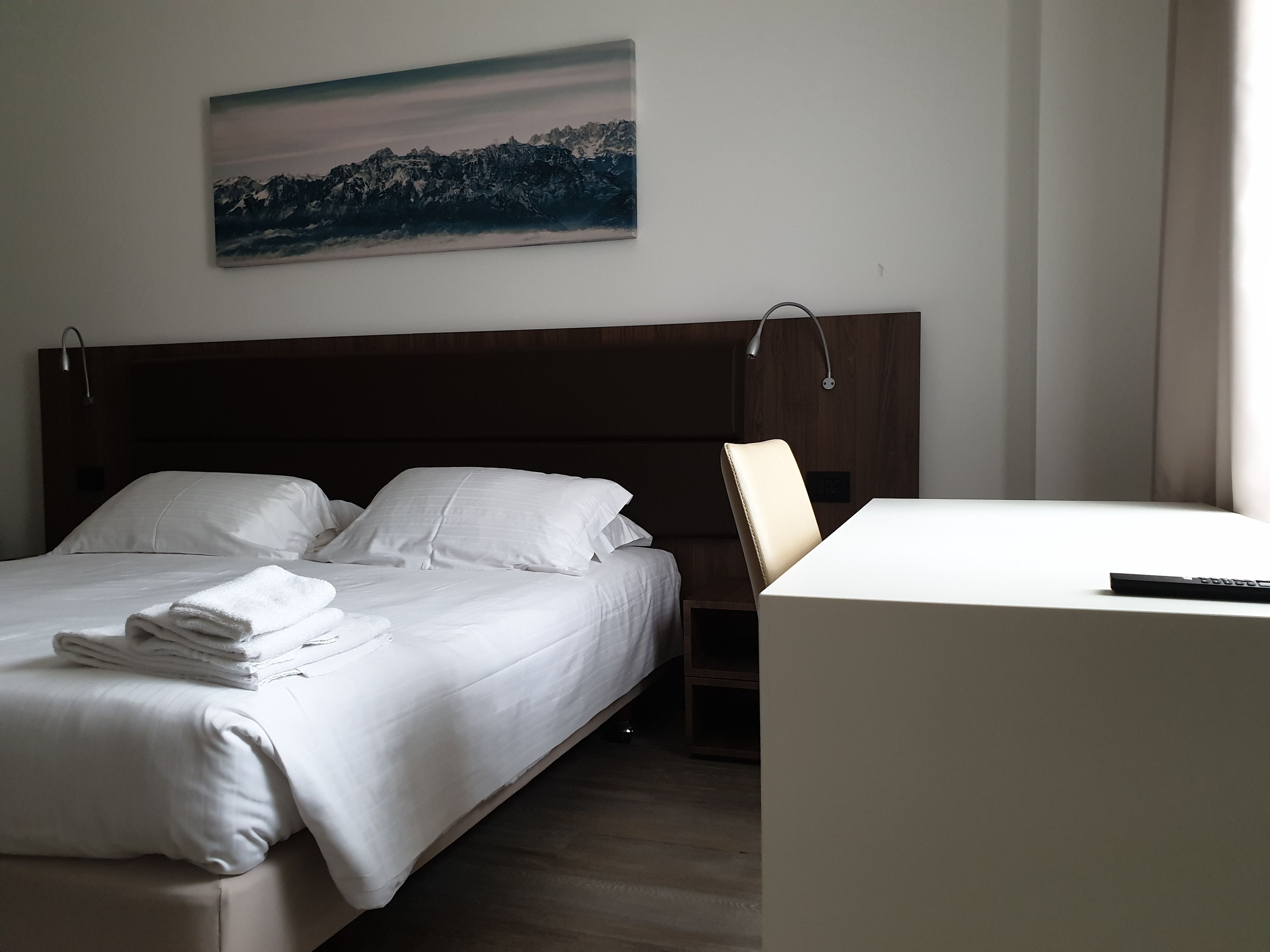 Ein Hotelzimmer mit Bett, Schreibtisch und einem Bild an der Wand.
