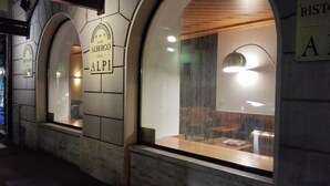 Un restaurante con ventanales arqueados y un letrero que dice "ALBERGO DELLE ALPI".