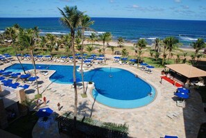 Een resort met een groot zwembad, strand en uitzicht op de oceaan.