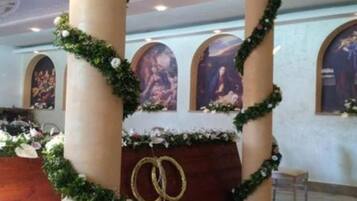 Interno di una chiesa con colonne ornate da vegetazione, un altare in legno e opere d'arte religiosa alle pareti.