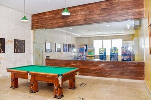 Una mesa de billar en una habitación con un muro de acento de madera y un ventanal grande.