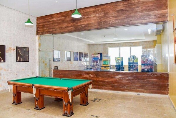 A pool table in a room with a wooden accent wall and a large window. - Grand Hotel Stella Maris (Palmi)