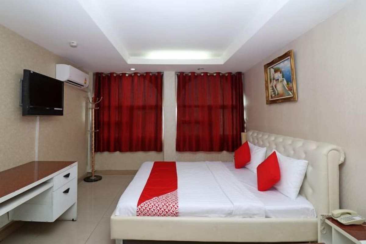 Una habitación de hotel con cama, escritorio, silla, televisión y un cuadro en la pared.