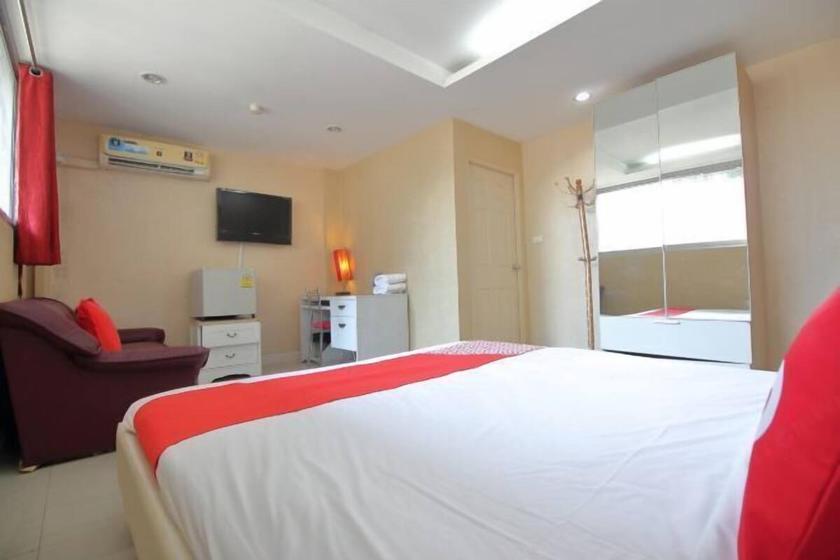Una habitación de hotel con cama, televisor, escritorio, silla y armario.