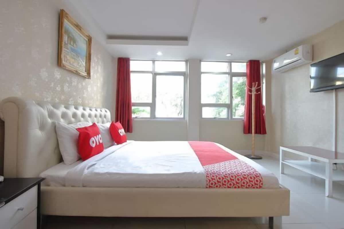 Habitación de hotel con cama, televisión, ventana con cortinas y aire acondicionado.