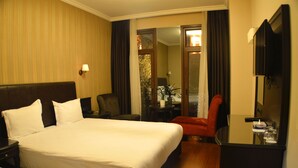 Una habitación de hotel con una cama grande, un escritorio, una silla y un televisor.