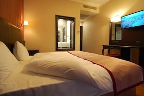 A hotel room with a bed, a television, and a window with a view.