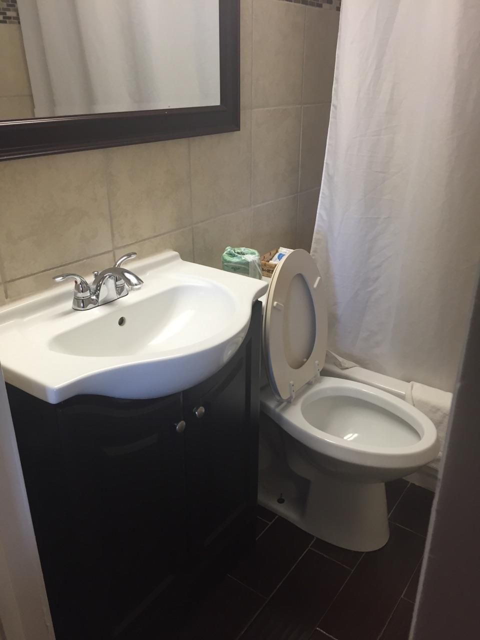 A bathroom with a white sink, a toilet, and a mirror above the sink.