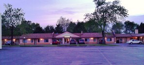 A motel with a central entrance, multiple parking spaces, and a parking lot.