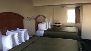 Une chambre d’hôtel avec deux lits, une petite table et une fenêtre avec des rideaux.
