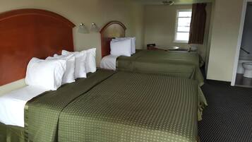 A hotel room with two beds, a small table, a mirror, and a window.