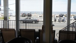 A view from a hotel room with a balcony overlooking a parking lot and the ocean.