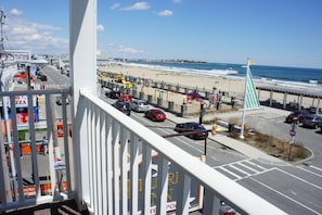 Vista desde un balcón sobre una playa, con una carretera y coches estacionados.