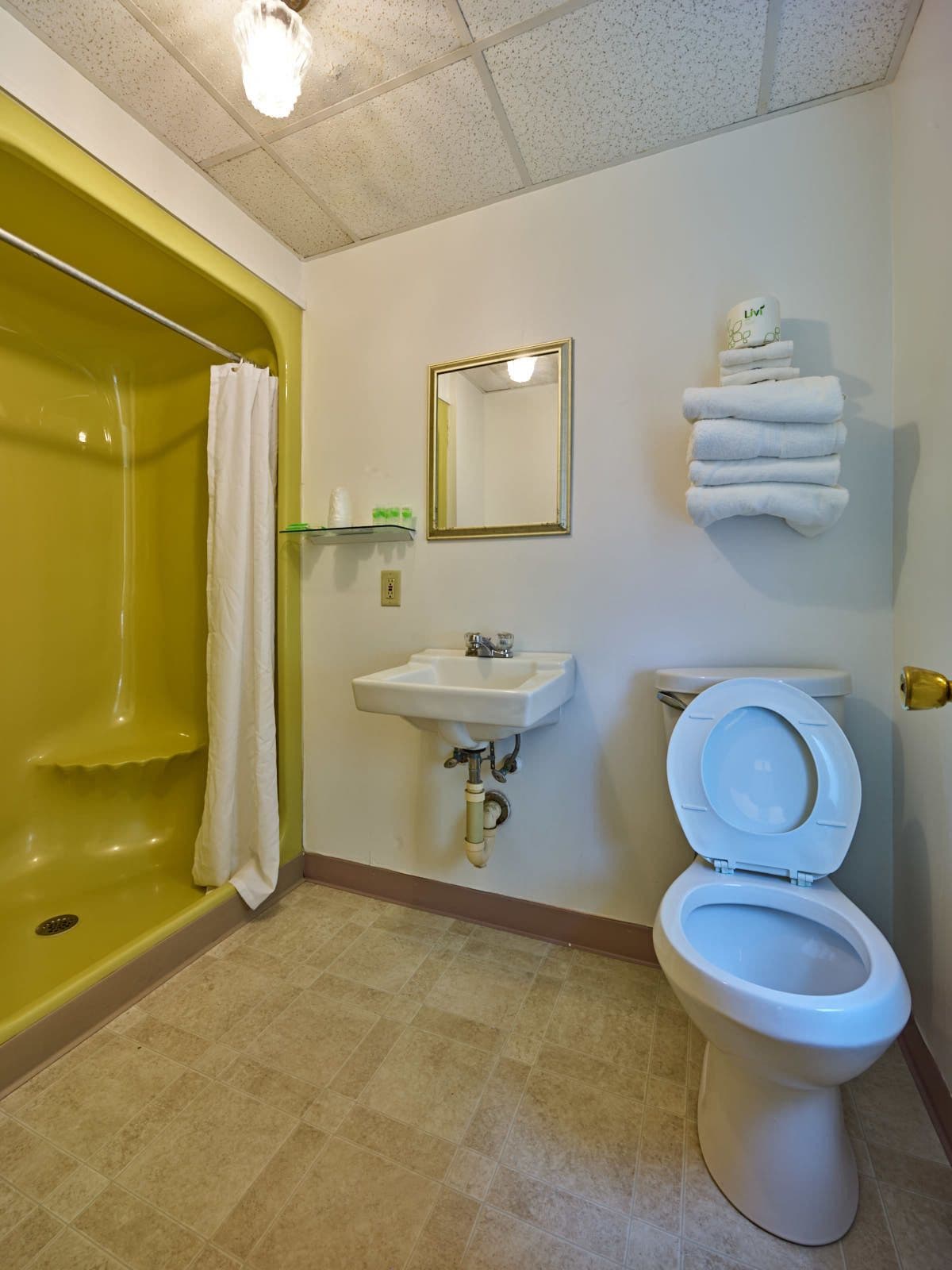 Un baño con una bañera amarilla, un lavamanos blanco, un inodoro y un espejo.