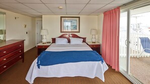 A hotel room with a bed, two bedside tables, a mirror, a painting, and a view of the outside balcony.