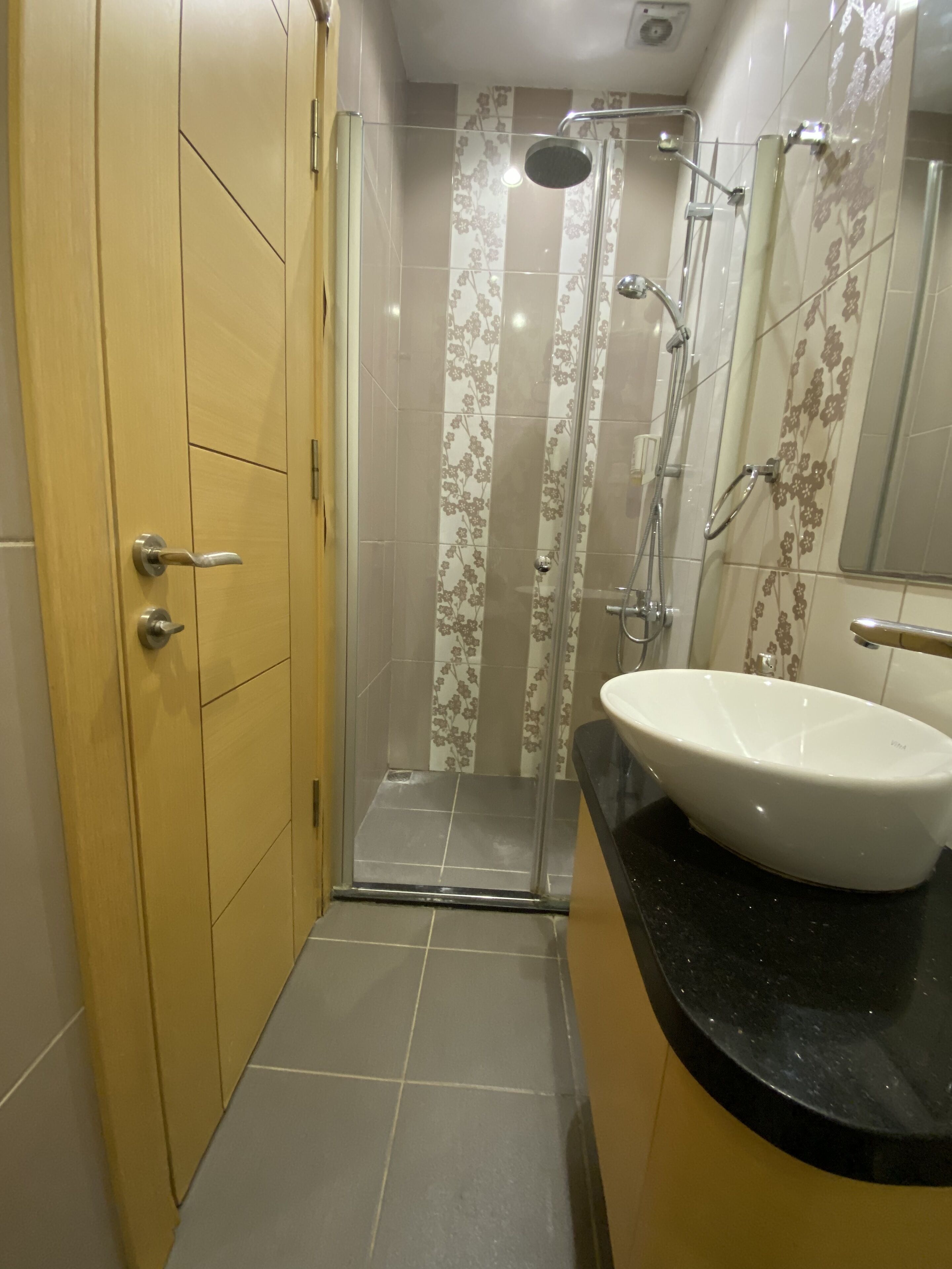 A bathroom with a shower, a sink, and a mirror.