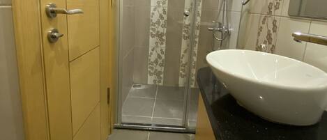 A bathroom with a shower, a sink, and a mirror.