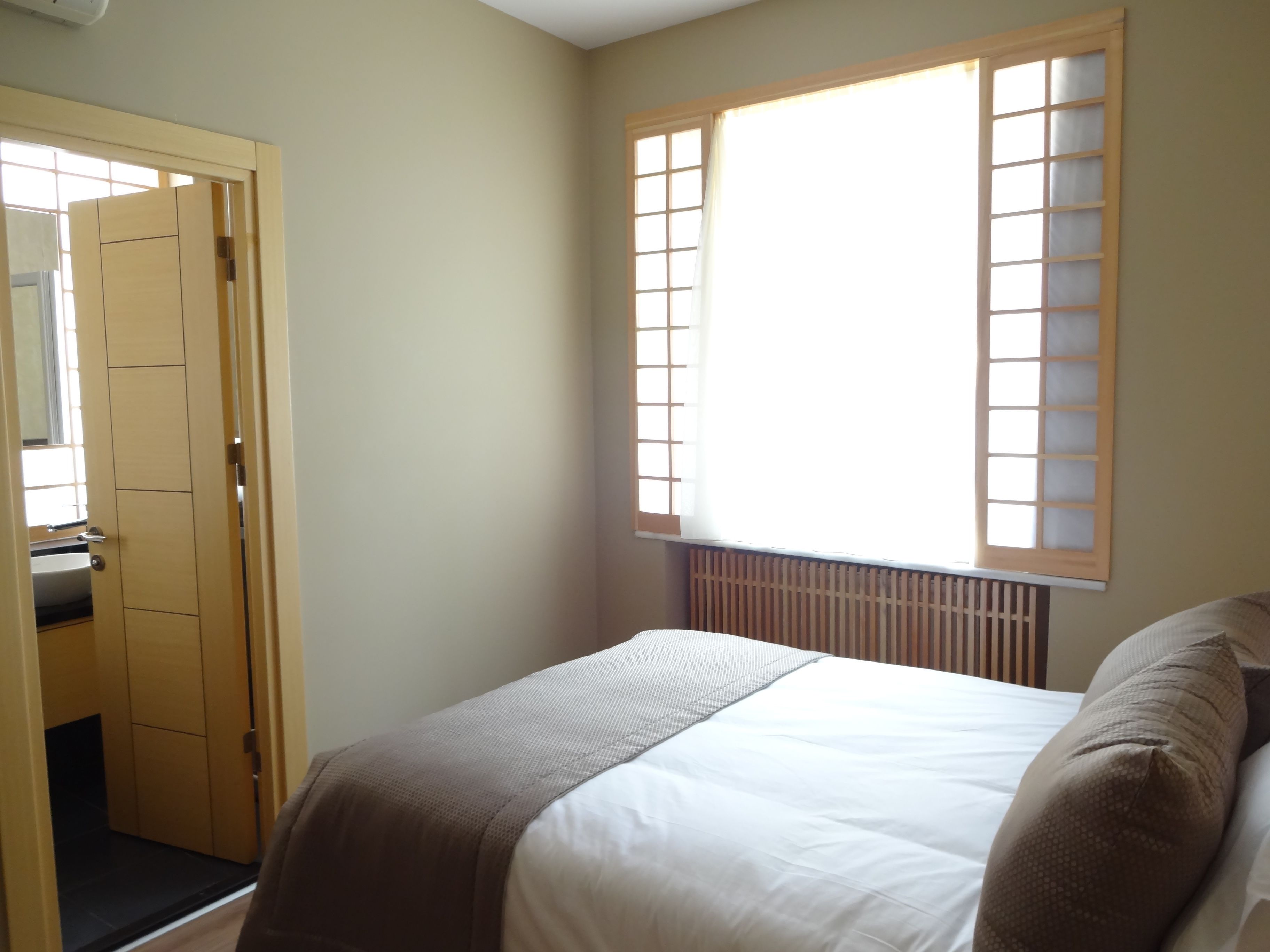 A bedroom with a bed, a window with a view, and a door leading to a bathroom.