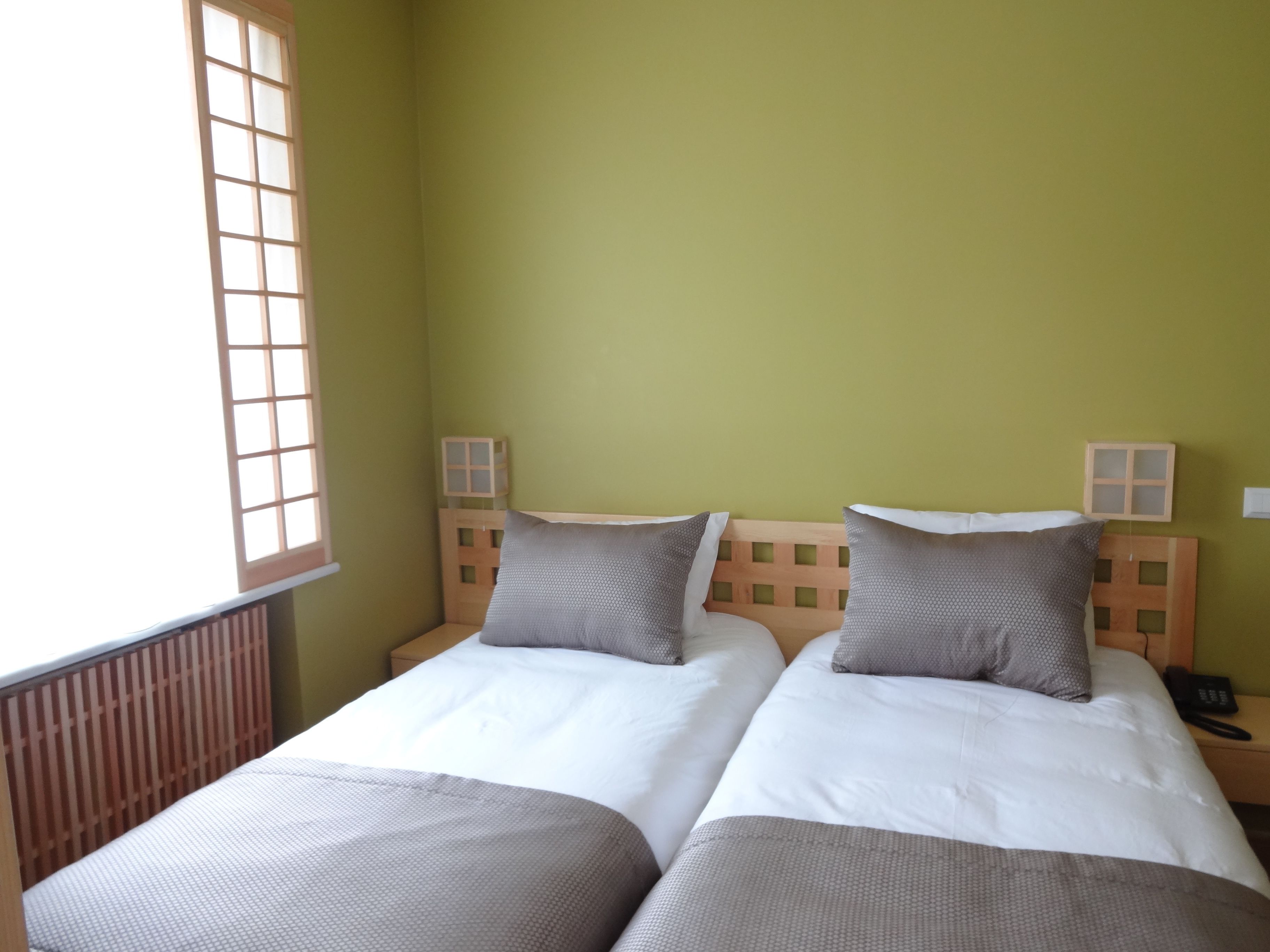 Una habitación con dos camas, una ventana y una mesita de noche con un teléfono.