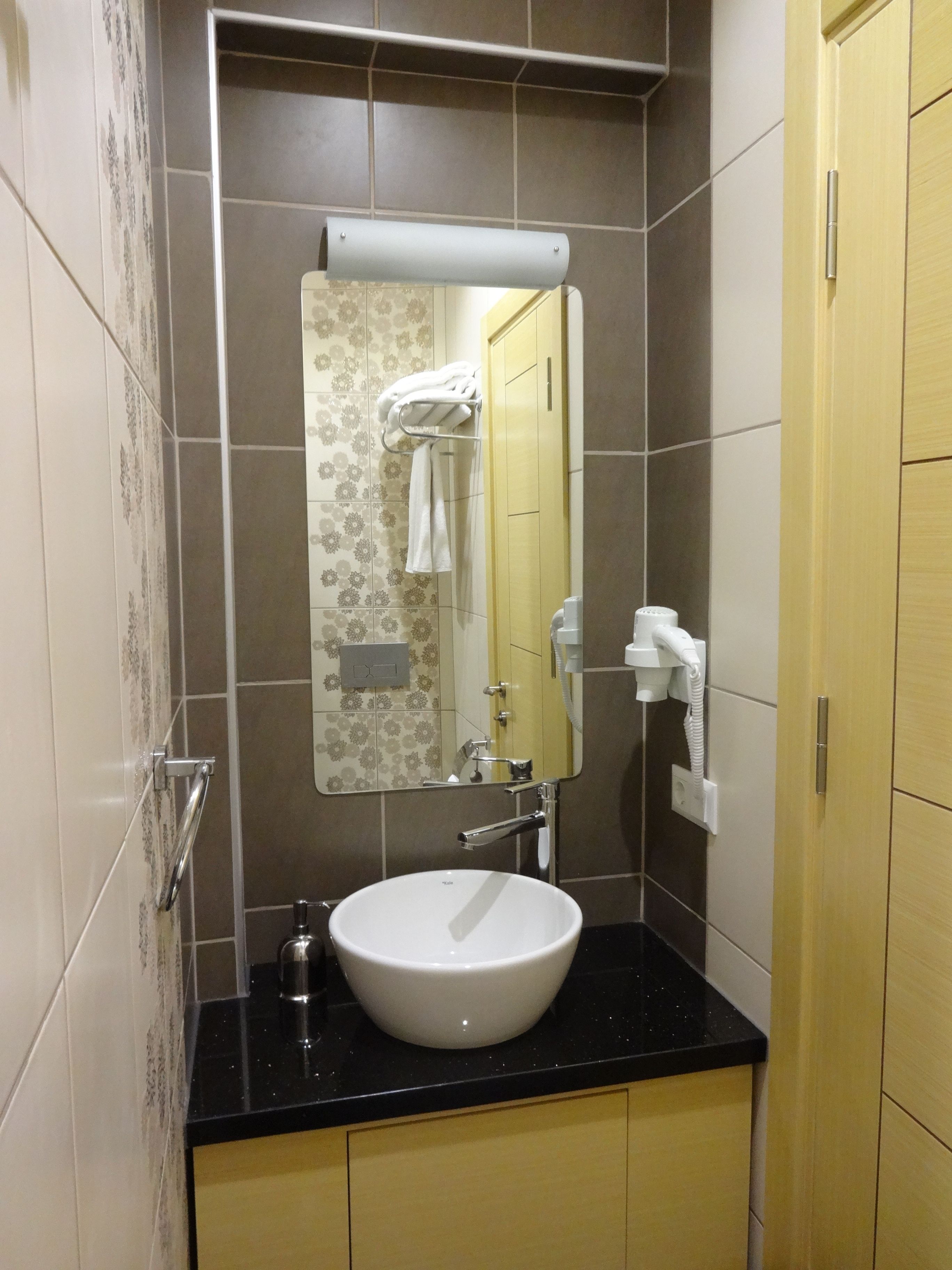 A bathroom with a white sink, a mirror, and a towel rack.
