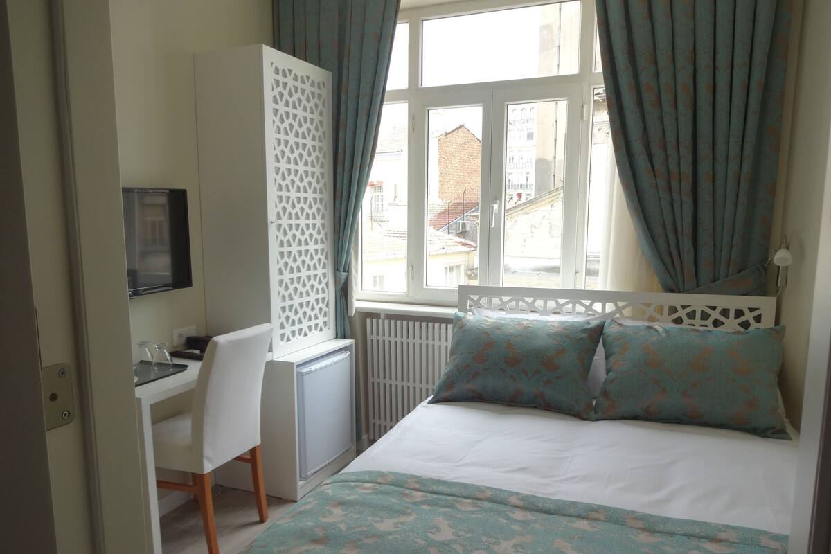 A bedroom with a bed, a desk, and a radiator.
