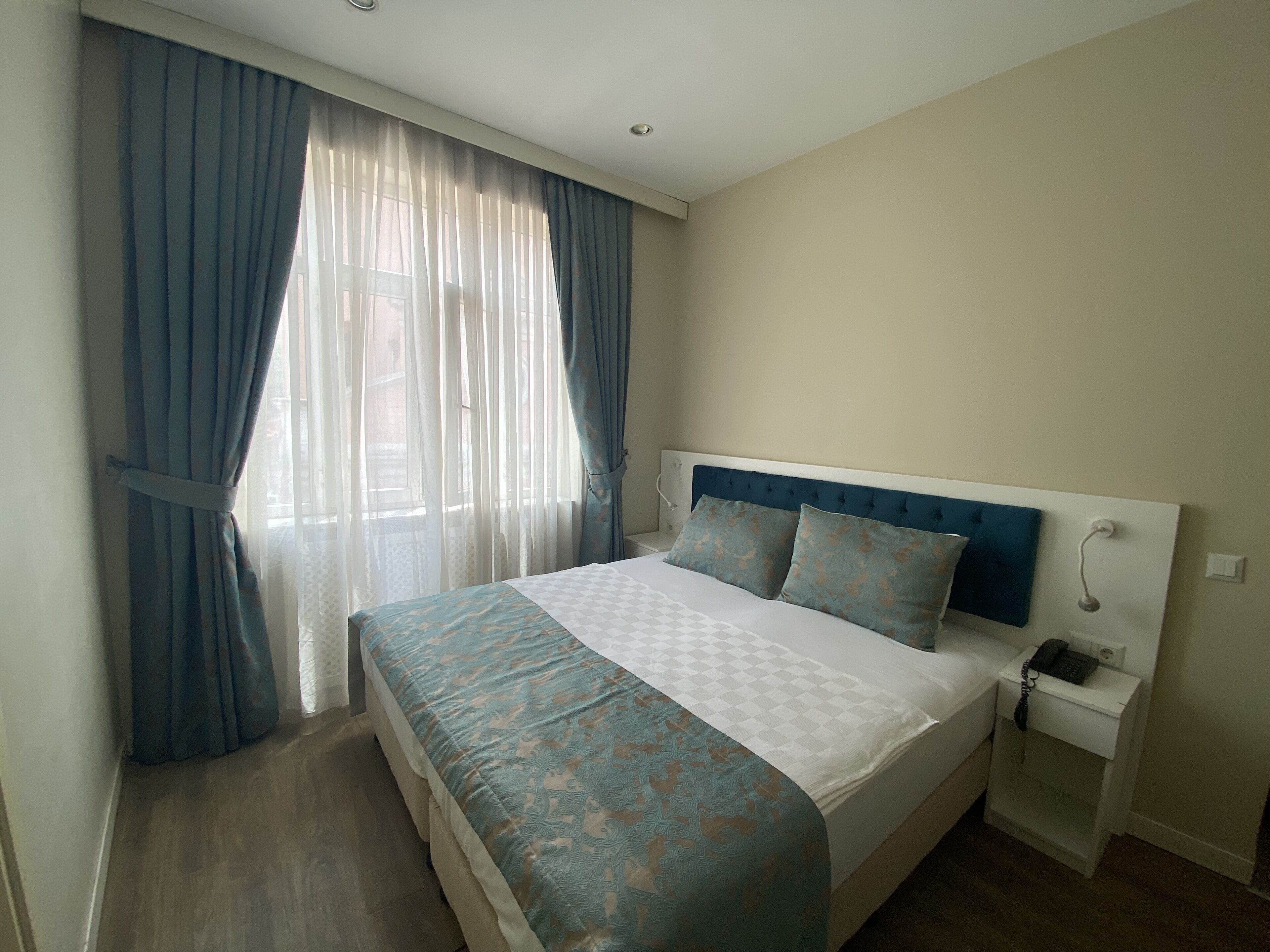 A bedroom with a bed, curtains, a bedside table, and a nightstand.