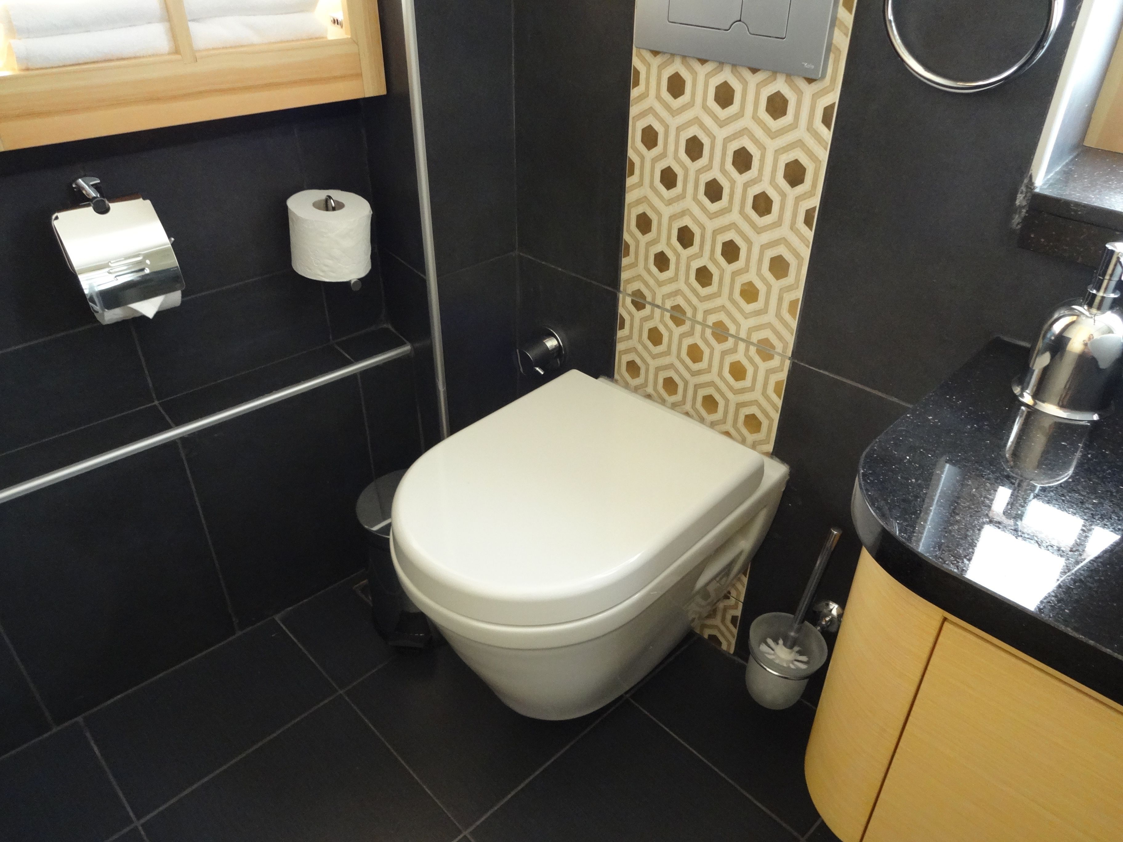 A bathroom with a toilet, a sink, and a mirror.