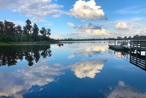 A calm lake with a dock and trees in the background.